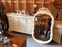 Wide view photo showing full dresser and matching mirror next to it in a garage setting.
