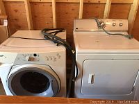 Front loading Whirlpool Duet Sport washer and Maytag Centennial dryer placed side by side, showing overall appliance condition and hose attachments.