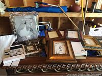 Photo showing multiple photo frames stacked together including glass and wooden frames with inserts