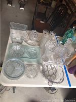 Full overview of the assortment on a white table including decanters, cocktail glasses, bowls, and vases