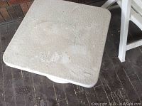 Close-up of the white plastic square table top showing textured surface and dirt marks.