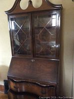 Full view of wooden secretary showing glass double doors with wooden lattice, closed writing surface, and curved bottom drawers.