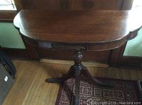 Semi-circular wooden entrance table with polished dark wood finish and carved floral detail on apron.