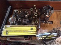Top-down view of assorted metal candleholders and a metal and glass elephant figurine on wooden floor.