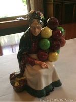 Front view of the Royal Doulton figurine showing the elderly woman holding colorful balloons and the basket at her side.