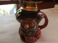 Ceramic character table lighter depicting Falstaff with detailed face and beard, brass lighter mechanism on top.