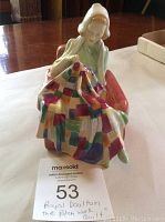 Front view of Royal Doulton figurine seated in armchair sewing patchwork quilt