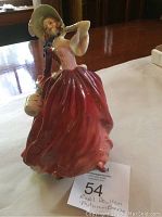 Front angle of Royal Doulton Autumn Breeze figurine showing full dress and bonnet details with basket in hand.