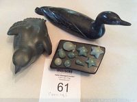 Set of three soapstone carvings: black loon with white details and broken tail, grey bird, black slab with starfish and shells carvings