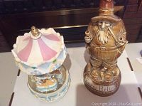 Photo showing carousel music box and farmer decanter side by side