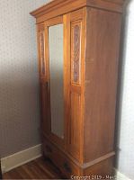 Full view of the breakaway wooden armoire with beveled glass and carved side panels