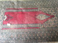 Close-up photo of red and beige wool area rug with geometric design.