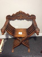 Front view showing carved wooden armrests ending in animal heads, slatted curved seat and detailed top backrest.