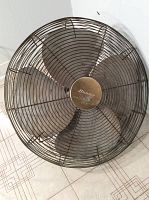 Front view of large industrial metal fan showing four blades and central Hunter brand logo on the hub, with visible wear and dust on fan blades and cage.