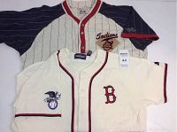 Two vintage baseball jerseys laid flat showing front design; Cleveland Indians with pinstripes and navy sleeves, Boston Red Sox in off-white with red 'B' and eagle patch