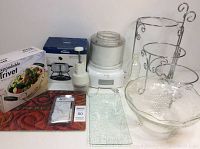 Overview photo showing all items including ice cream maker, glass bowl, metal stand, placemats, water bottle, and boxed trivet.