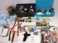 Overview of various sewing and craft supplies including scissors, thread spools, yarn, pins, needles, measuring tools, and storage tins.