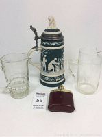 Four items displayed on white surface: Villeroy & Boch ceramic stein, leather covered metal flask, clear glass pitcher, textured glass beer mug.