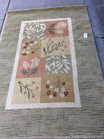 Overhead view of a rectangular 7x5 ft area rug with a central floral and leaf pattern panel and green outer border, placed on a flat surface.