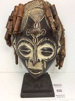 Front view of the wooden tribal mask showing carved patterns and attached wooden beads.
