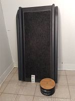 Front view of folded extendable pet ramp in black with textured surface and biscuits treat jar in front.