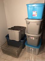 Photo showing stacked plastic storage bins of various sizes and two metal wire crates on the floor.