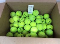 Top-down view of the box filled with used tennis balls showing various visible brands including Penn and Wilson.