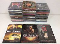 Photo of stacked DVDs and CDs displaying movie covers The Island, War of the Worlds, and Red Eye.