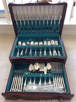 Overall view of open wooden box with two-tier insert showing all compartments filled with cutlery
