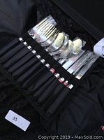 Close-up of forks, spoons, and knives with black handles organized in a carrying case