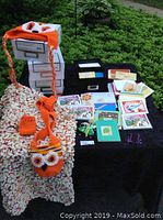 Lot items on display outdoors on a black table including crochet scarf, greeting cards, earrings, and photo boxes.