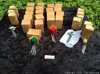 Group of tiny wind chimes in cardboard boxes arranged by type, including birdhouse-shaped toppers in red and green, and a few loose wind chimes