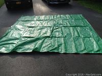 Photo of green tarp spread out flat on pavement, showing size and condition