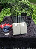 Photo showing the full lot including the black metal dog crate, navy Yankees hat with ear holes, red and blue striped polo shirt, and two PetSafe timed feeding dishes.