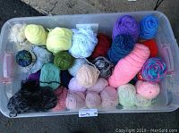 Large container with multiple skeins and balls of yarn in various colors and textures