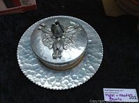 Close-up of hammered metal bowl with glass insert and metal sculptured rose lid