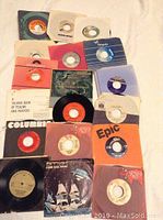 Collection of 45 RPM vinyl records in their original sleeves, showing some wear and use.