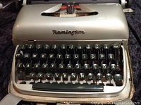 Front view of portable Remington typewriter showing QWERTZ keyboard with black round keys and metal body.