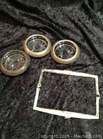 Three round antique coasters with sterling silver rims and glass bottoms on black fabric