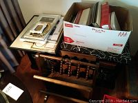 Overview of picture frames on tabletop and next to wooden magazine rack with box of photo albums on top