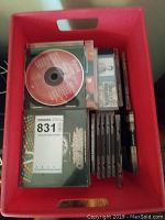 A red container holding multiple CDs in jewel cases, including some with visible cover art.
