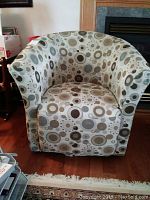 Front view of upholstered swivel tub chair with patterned fabric and slight wear on seat.