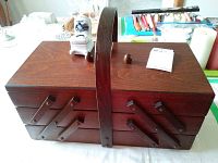 Closed view of wooden 3-tier sewing box with central handle, showing intact exterior with rich brown wood finish.
