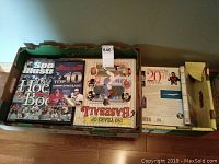 Top view of the box containing three large hardcover books, including Sports Illustrated hockey and baseball books and a 20th-century encyclopedia volume.
