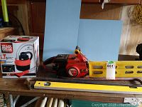 Wide shot showing all items included: chainsaw, level, two crowbars, and boxed auto vacuum