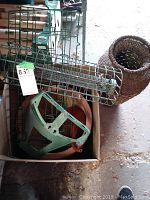 Photo showing contents of box with hose caddy and wire hanging racks along with clay pot visible.