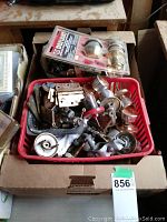 Box filled with assorted door hardware including knobs, locks, hinges, and gate hardware.