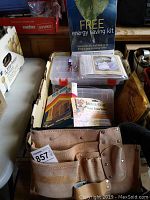 View of leather tool belt and clear plastic organizer boxes with dividers, some packaging and pamphlets seen