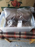 Packed brown mesh fabric side walls and coiled chains in plastic bin.