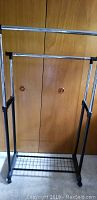 Front view of metal adjustable clothes rack showing two rods for hanging clothes and bottom rack.